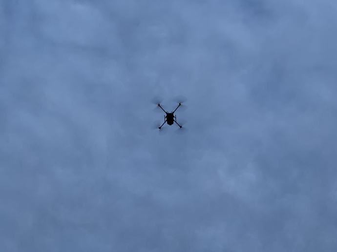 a drone flies overhead under a cloudy sky